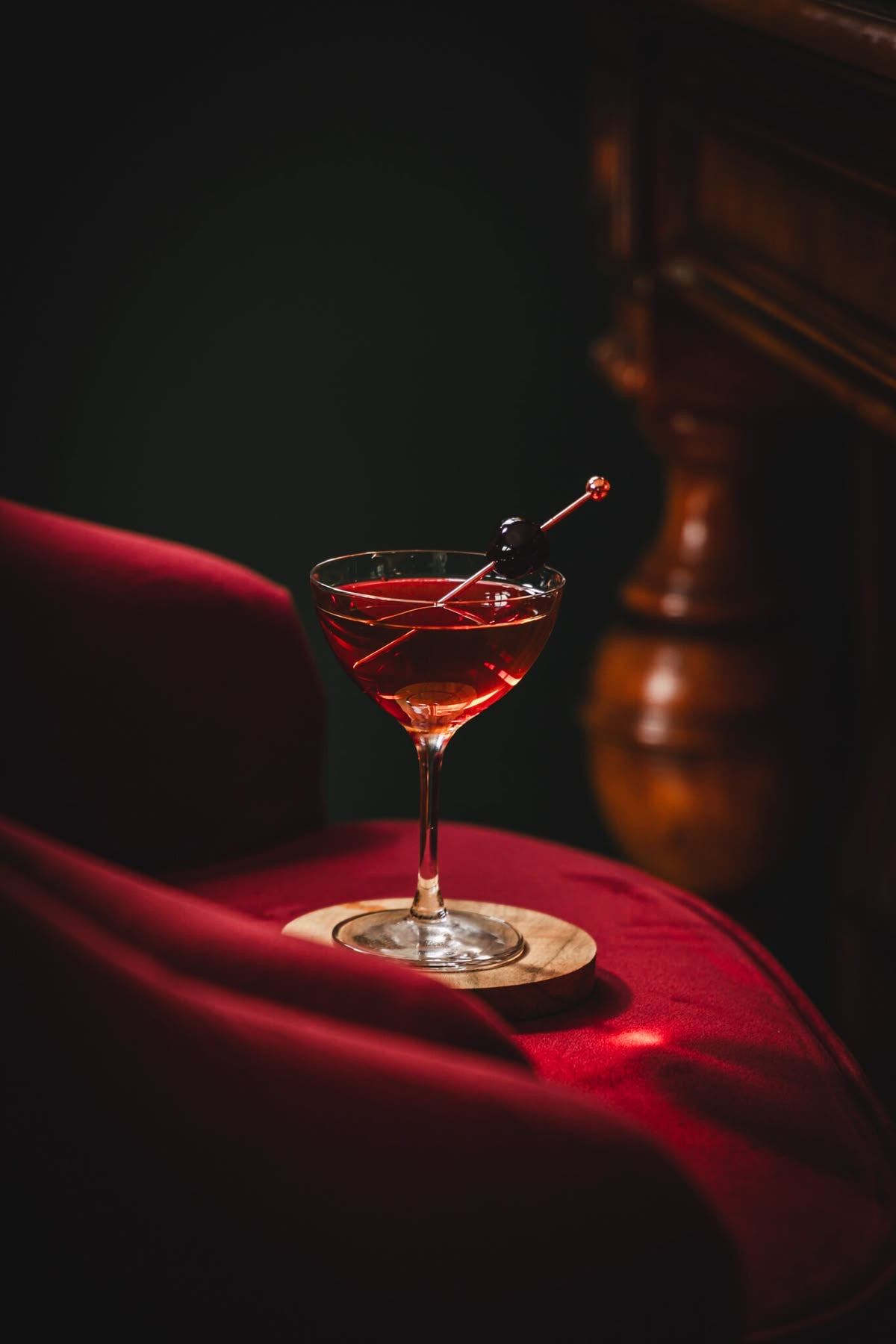 A red cocktail with a cherry on a red velvet armrest