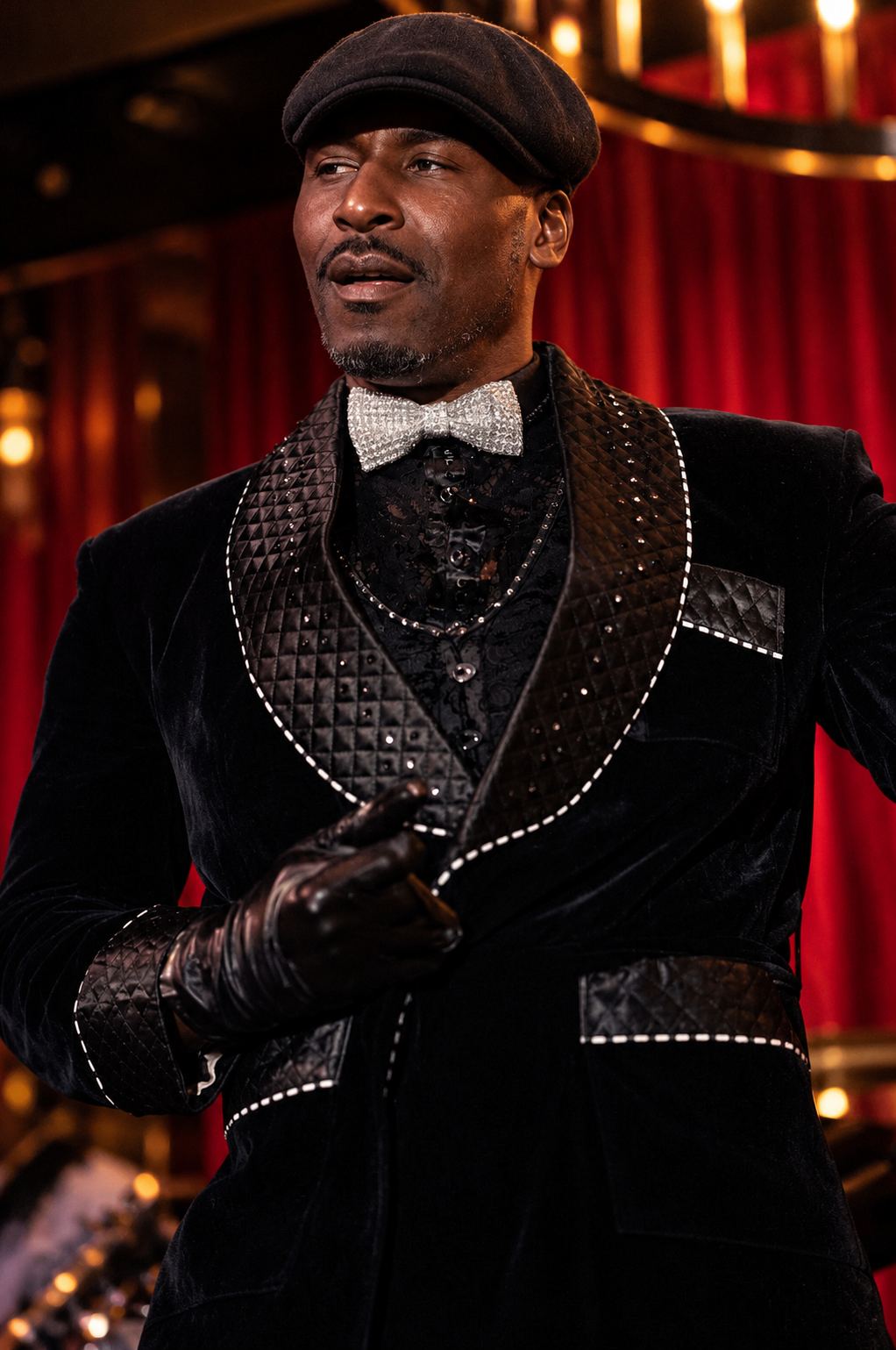 A performer in a velvet jacket before the red curtain
